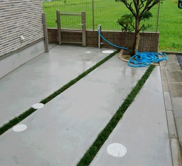 土間コンクリートの駐車場と、目地に植えられた芝生の施工事例