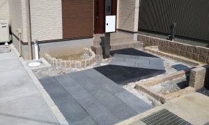 石材を敷き詰めたアプローチ階段と、レンガ積みの花壇